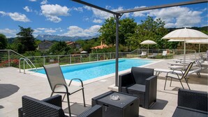 A poolside area with lounge chairs and umbrellas, surrounded by a metal railing and a view of mountains in the background. - Awesome home in Montefalcone Appennino (Montefalcone Appennino)