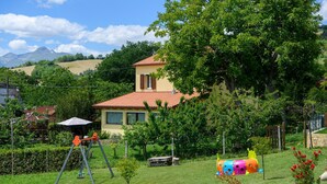 A house with a red-tiled roof, surrounded by lush greenery and a playground. - Awesome home in Montefalcone Appennino (Montefalcone Appennino)