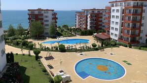 Un complejo residencial con piscina, zona de juegos infantiles y vistas al mar.