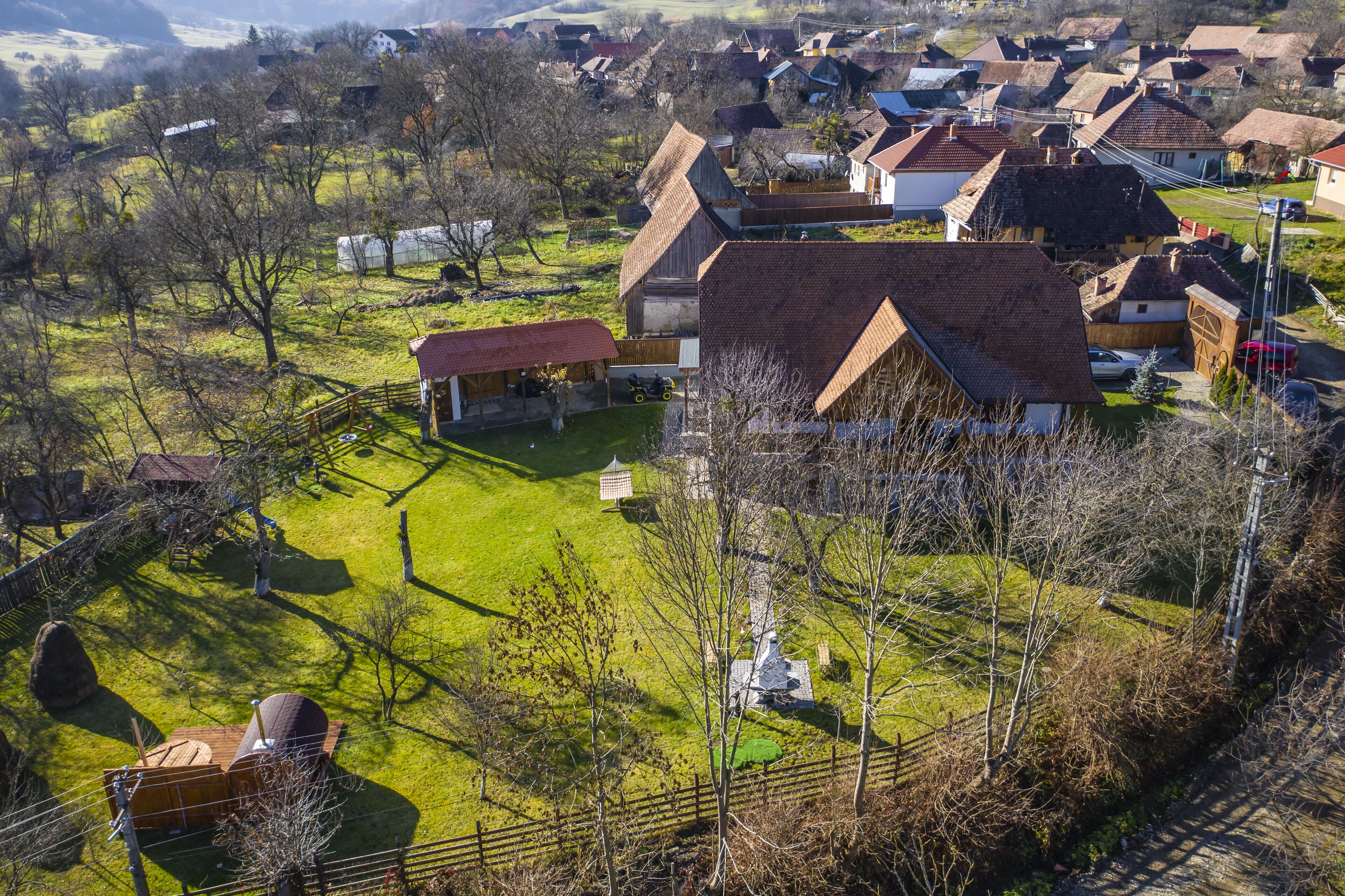 A rural village with houses, a barn, and a fenced area with a tractor.