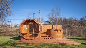 Een houten hut met een ronde deur, een klein terras en een houten dek.