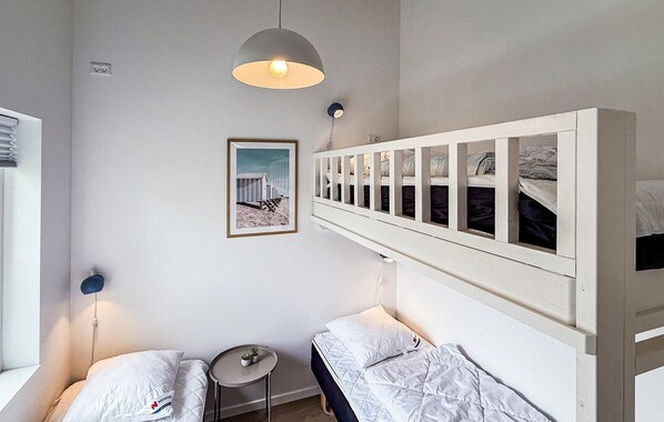 A room with bunk beds, a small round table, and a wall-mounted light fixture.