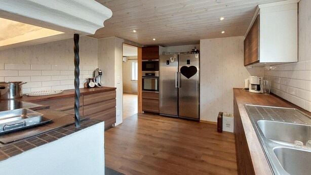 Una cocina moderna con suelo de madera, electrodomésticos de acero inoxidable y un diseño con forma de corazón en el refrigerador.