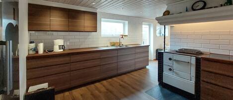 A modern kitchen with wooden cabinets, a large island, and a built-in oven.