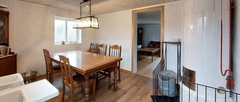 A dining area with a wooden table and chairs, a hanging light fixture, and a view of a living room through an open doorway.