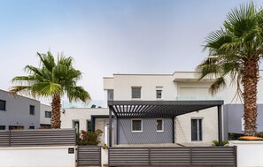 Un edificio residencial moderno con techo plano, ventanas amplias y un área exterior cubierta.