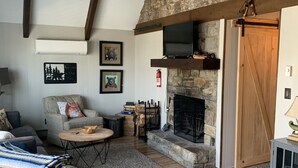 A cozy living room with a stone fireplace, wooden beams, and a comfortable seating area. - Pine Ridge retreat on Beech Mountain, quiet with fireplace and mountain views! (Beech Mountain)