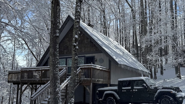 A cabin with a wooden deck and stairs, surrounded by snow-covered trees. - Pine Ridge retreat on Beech Mountain, quiet with fireplace and mountain views! (Beech Mountain)