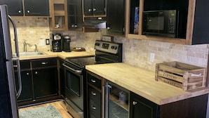 A modern kitchen with dark cabinetry, a stainless steel refrigerator, a microwave, and a built-in oven. - Pine Ridge retreat on Beech Mountain, quiet with fireplace and mountain views! (Beech Mountain)