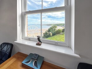 Ein Fenster mit Blick auf einen Strand, ein Riesenrad und eine kleine Figur auf einem Regal.
