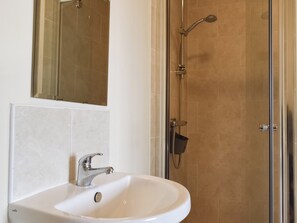 Une salle de bain avec un lavabo blanc, un miroir et un espace douche.