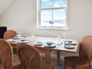 Une table à manger avec de l’assiette bleue et blanche, des verres et un ensemble de chaises en osier.