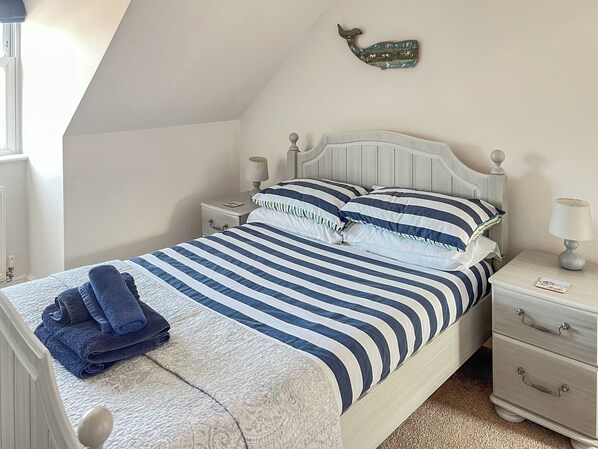 Une chambre à coucher avec un lit, des tables de chevet, une lampe, un élément de décoration murale et une fenêtre.