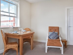 A dining area with a wooden table, wicker chairs, and a cushioned chair with a striped pillow.