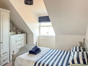 Ein Schlafzimmer mit Bett, Schminktisch, Fenster und Heizkörper.