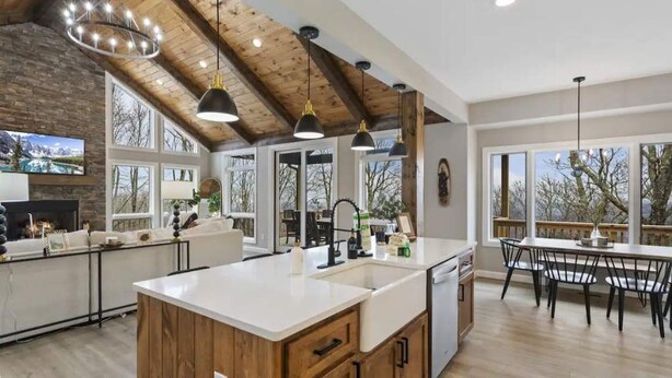 A spacious kitchen with a large island, wooden beams on the ceiling, and a dining area with a view. - Mountain view’s with hot tub & pool table on Beech Mountain. Sleeps 10.  (Banner Elk)