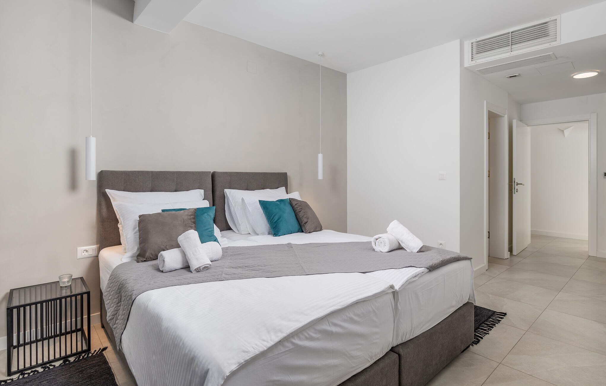 Ein modernes Hotelzimmer mit einem großen Bett, einem Nachttisch und einem begehbaren Kleiderschrank.