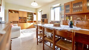 A spacious kitchen with wooden cabinets, a dining table, and a television. - Cozy home in Metato with kitchen (Metato)