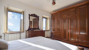 A bedroom with a large bed, wooden wardrobe, and a dresser. There are windows with views of the sky. - Cozy home in Metato with kitchen (Metato)