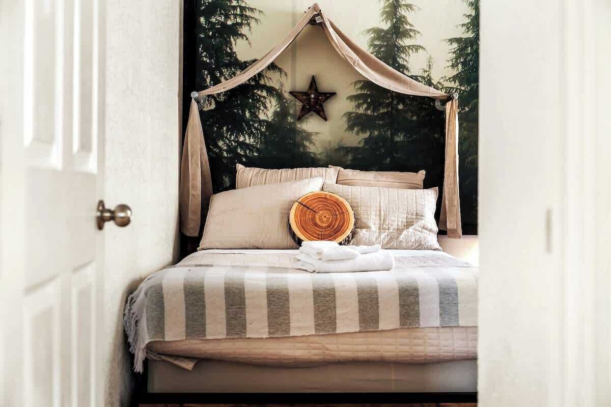 A bed with a canopy, a star decoration, and a tree bark pillow.