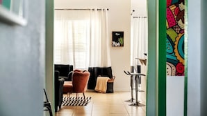 A modern living room with a sofa, a chair, a coffee table, and a side table. There is a window with curtains, a wall-mounted picture frame, and a colorful wall decoration. - Heated Pool | Game Room | Themed Rooms | Disney (Davenport)