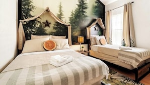 A bedroom with two beds, a canopy bed, a star decoration, a lamp, and a forest mural on the wall. - Heated Pool | Game Room | Themed Rooms | Disney (Davenport)