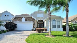 A two-story house with a stone facade, a garage, and a well-maintained lawn. - Heated Pool | Game Room | Themed Rooms | Disney (Davenport)