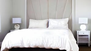 Une chambre à coucher avec un grand lit, deux tables de chevet et une tête de lit.