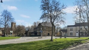 Une rue bordée d’un bâtiment historique, d’une tour de l’horloge et d’un immeuble d’habitation moderne.