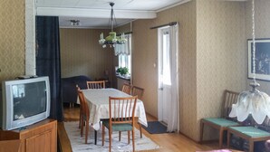 Un comedor con mesa, sillas, televisor y candelabro.