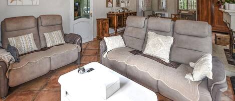 A living room with two sofas, a coffee table, and a dining area in the background.