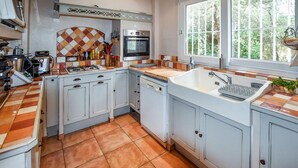 A kitchen with white cabinets, a tiled backsplash, a built-in oven, and a window with a view of greenery. - Pet friendly home in Entraigues-sur-la-Sorg (Entraigues-sur-la-Sorg)