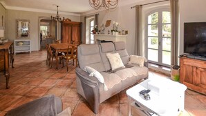 A living room with a grey sofa, a dining table with chairs, a TV, and a fireplace. - Pet friendly home in Entraigues-sur-la-Sorg (Entraigues-sur-la-Sorg)