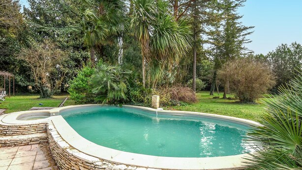 A swimming pool with a stone border, surrounded by lush greenery and trees. - Pet friendly home in Entraigues-sur-la-Sorg (Entraigues-sur-la-Sorg)