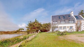 Une maison à deux étages avec une façade en pierre, un toit en pente et une cheminée bien visible.
