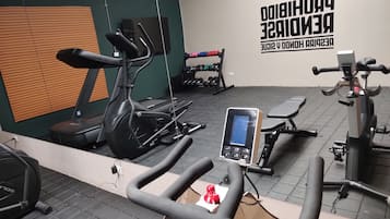 Un gimnasio con equipo de ejercicio, una pared con texto motivacional y un banco.