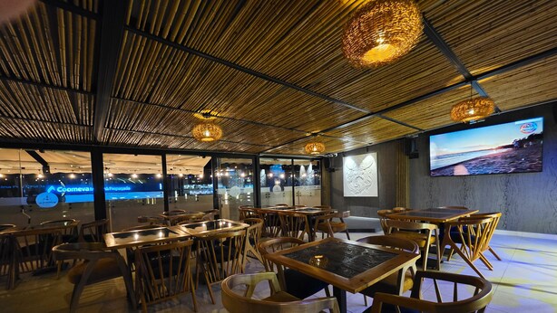 Un ristorante con soffitto in bambù, tavoli e sedie in legno.