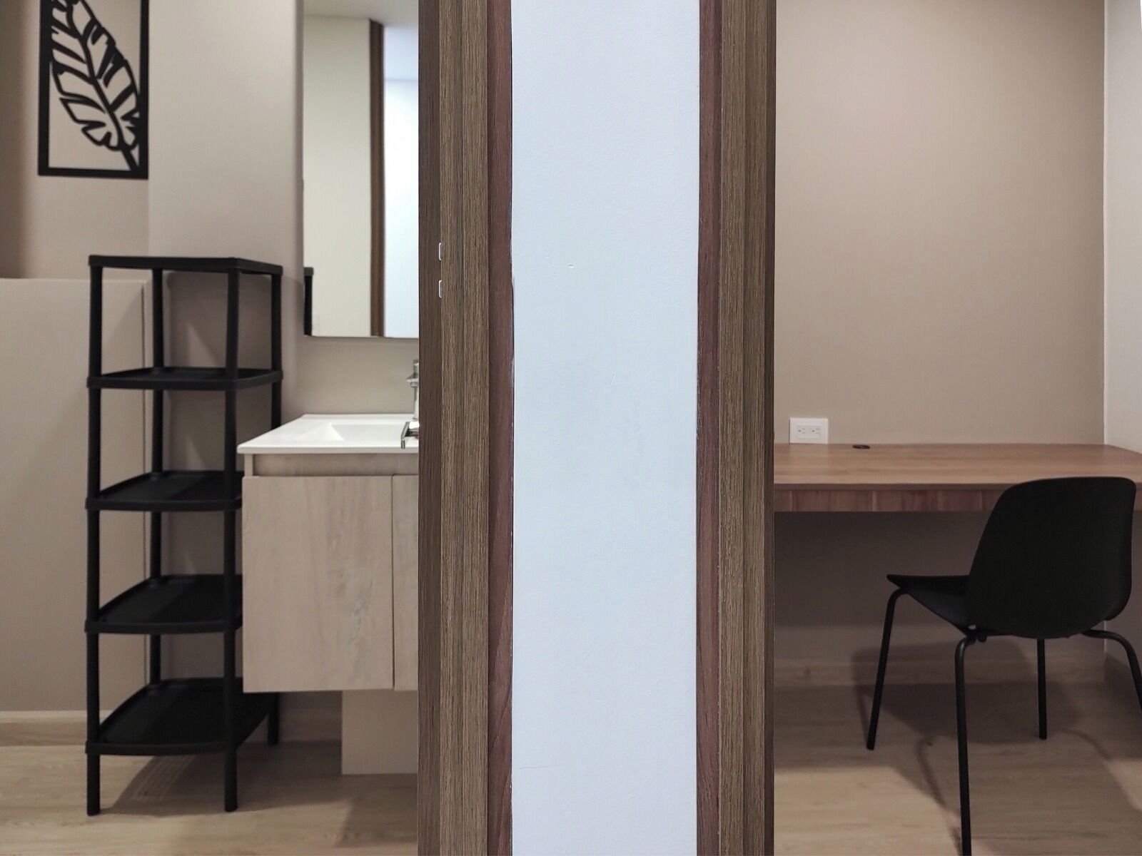 A modern bathroom with a wooden vanity, a black shelving unit, and a black chair.