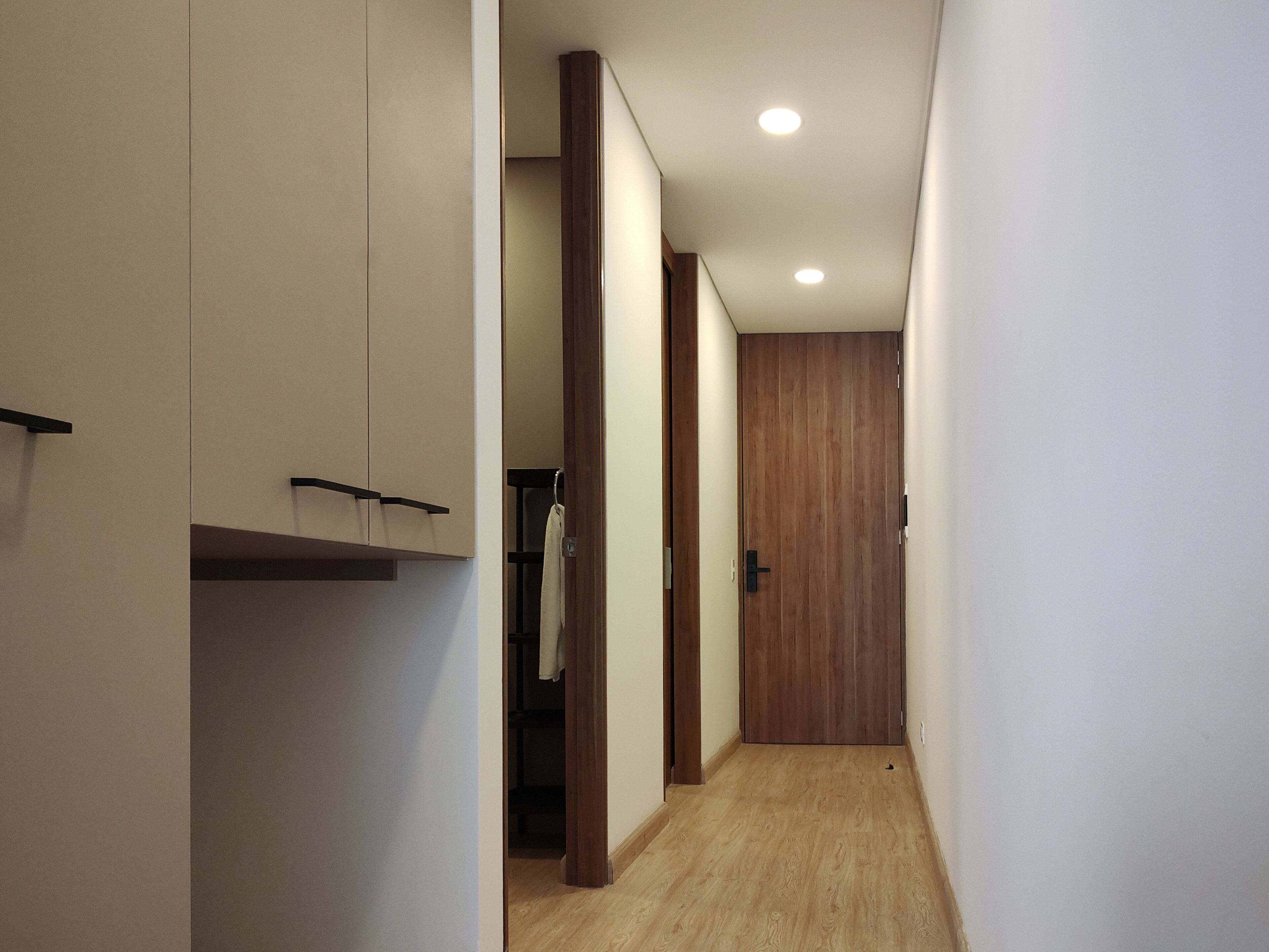 A narrow hallway with wooden doors and a wooden floor.