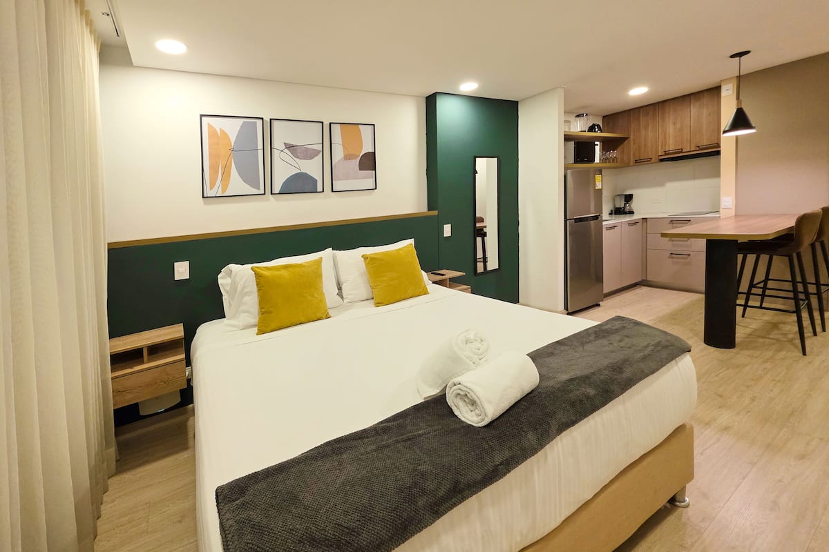 Une chambre d’hôtel moderne dotée d’un grand lit, d’une petite kitchenette et d’un coin repas.