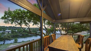 A wooden deck with a table and chairs overlooking a lake and trees.