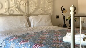 Un letto con una coperta a fiori, una testiera bianca e una lampada da comodino.