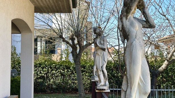 Una statua di una donna in abito bianco, una statua di un uomo e un edificio con struttura in cemento.