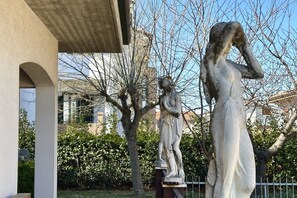 Una estatua de una mujer con vestido blanco, una estatua de un hombre y un edificio con estructura de concreto.