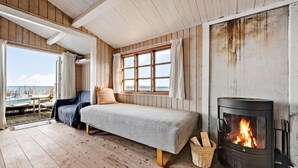 Acogedora habitación tipo cabaña con cama, chimenea y vista a la playa.