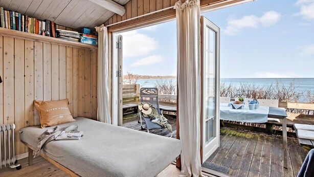 Una habitación acogedora con una cama, una estantería y vistas al mar.