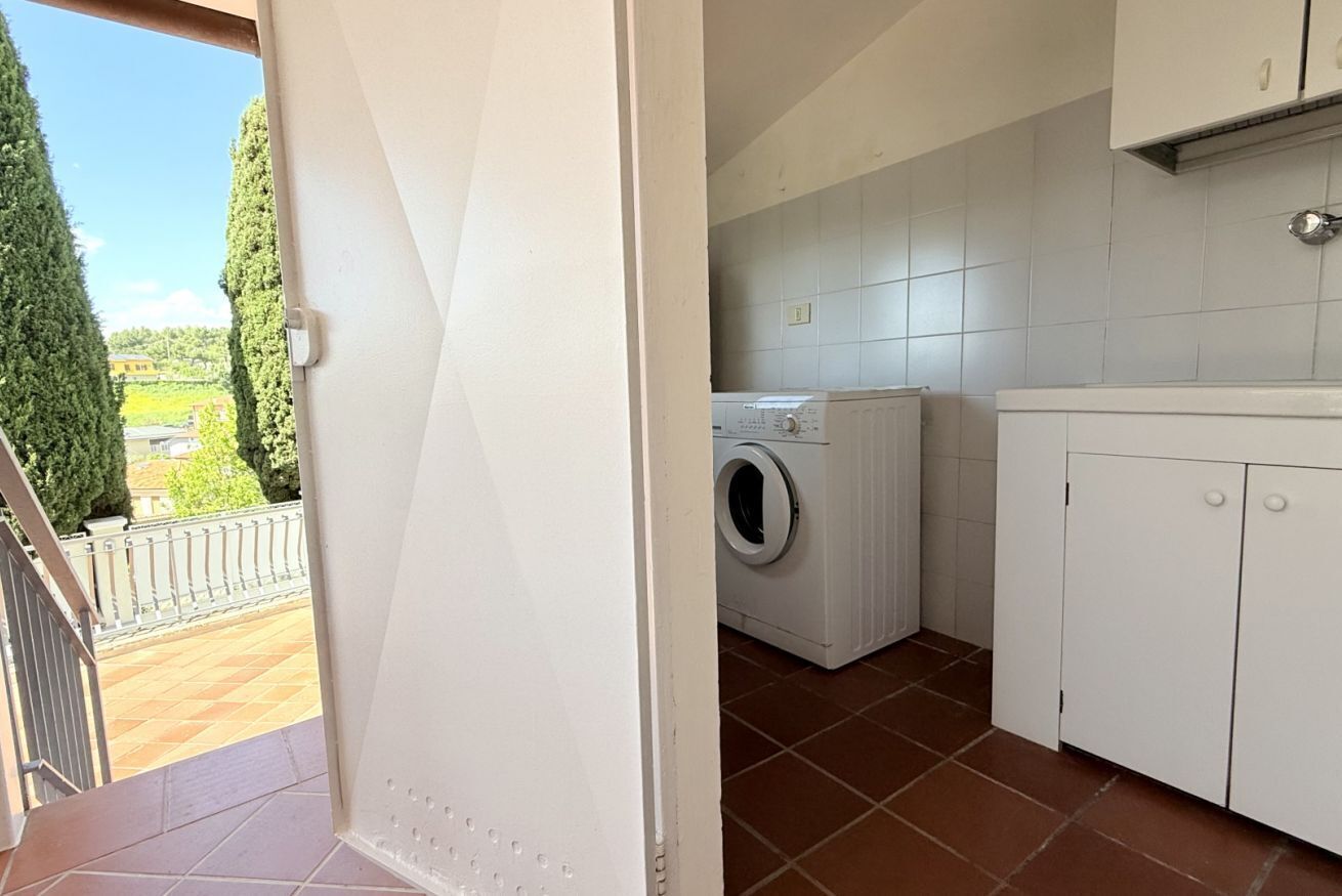 A laundry room with a washing machine, a drying rack, and a cabinet.