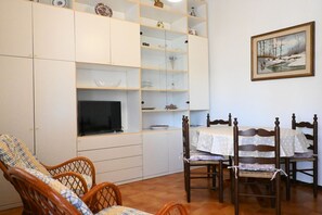A living room with a TV, wooden chairs, a dining table, and a bookshelf. - N278 - Numana, delightful two-room apartment in the historic centre (Numana)