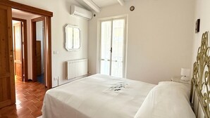 Ein Schlafzimmer mit Bett, Heizkörper, Fenster und Tür.