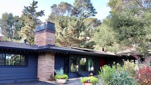 A modern house with a brick chimney, large windows, and a covered porch with outdoor seating. - Designer Retreat w/ Hot Tub, Huge Backyard Oasis (Santa Cruz)